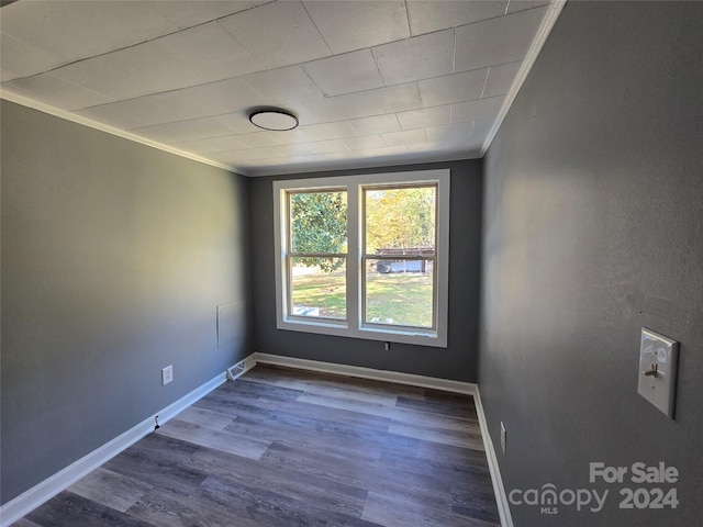 spare room featuring ornamental molding and dark wood-type flooring