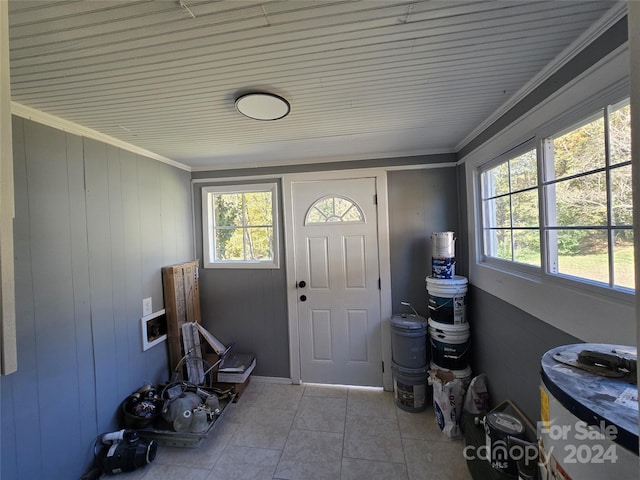 tiled foyer featuring crown molding, a healthy amount of sunlight, and wooden walls