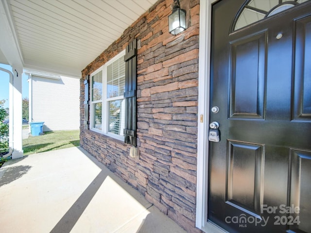 entrance to property with covered porch and stone siding