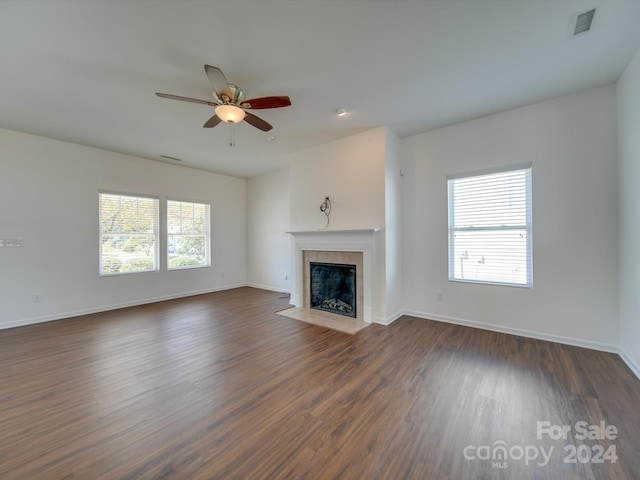 unfurnished living room featuring ceiling fan, visible vents, baseboards, dark wood finished floors, and a tiled fireplace