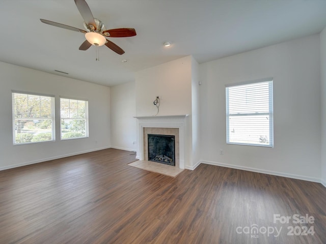 unfurnished living room featuring ceiling fan, a fireplace, and dark hardwood / wood-style flooring