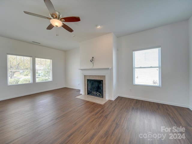 unfurnished living room with dark wood-style floors, a ceiling fan, baseboards, and a fireplace