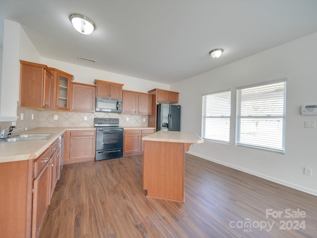 kitchen featuring decorative backsplash, a kitchen island, dark wood-type flooring, sink, and black appliances