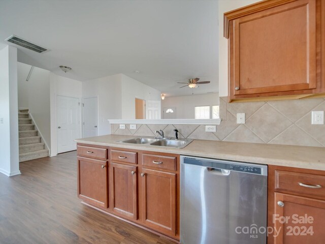 kitchen featuring wood finished floors, stainless steel dishwasher, decorative backsplash, a sink, and visible vents