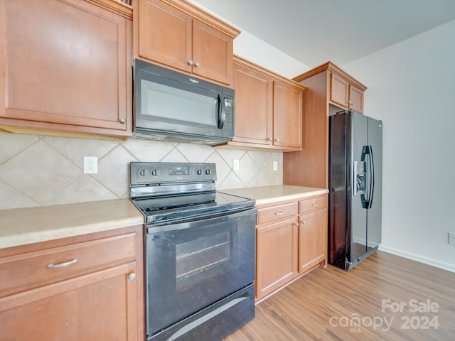 kitchen featuring black appliances, decorative backsplash, and light wood-type flooring