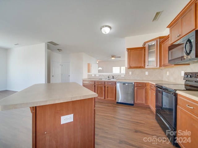 kitchen with dark hardwood / wood-style floors, backsplash, black appliances, a center island, and ceiling fan