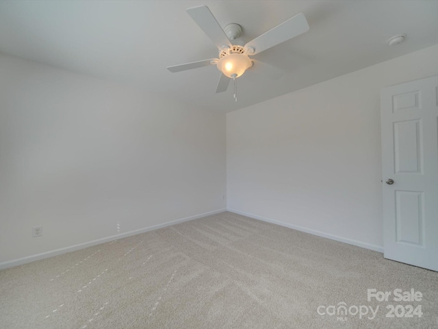 spare room with a ceiling fan, light colored carpet, and baseboards
