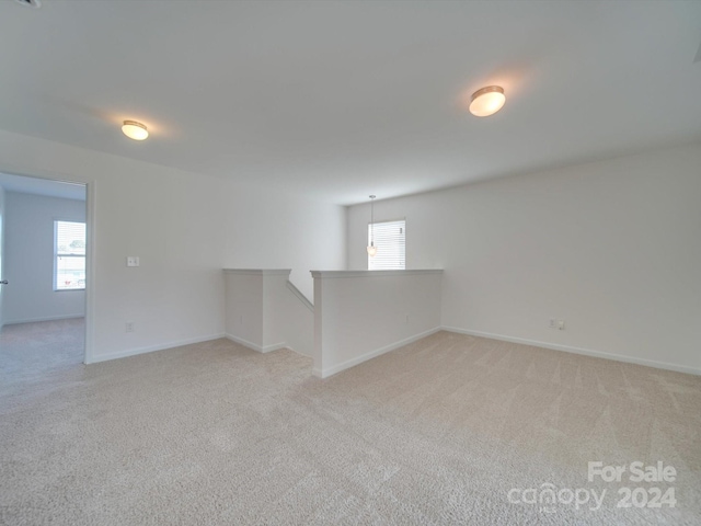 interior space with baseboards, light colored carpet, and a healthy amount of sunlight