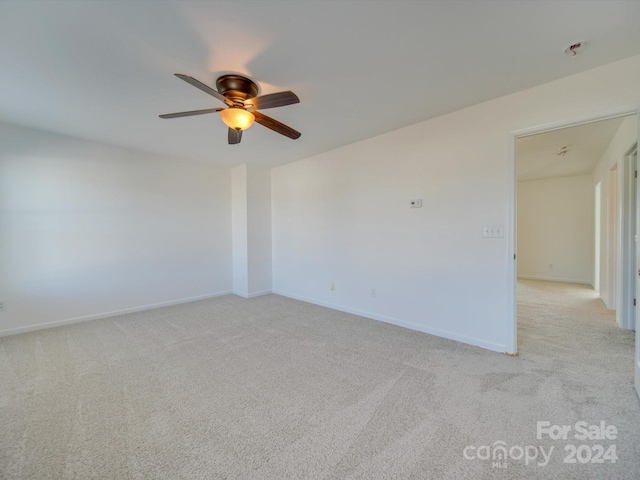spare room with baseboards, light carpet, and ceiling fan