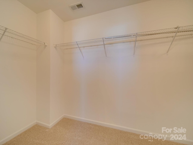 walk in closet featuring visible vents and light carpet
