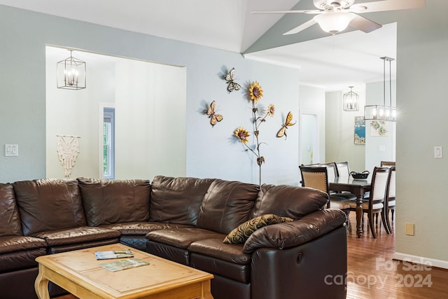 living room featuring lofted ceiling, ceiling fan with notable chandelier, and hardwood / wood-style floors