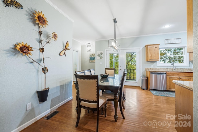 dining room featuring crown molding, light wood-type flooring, and french doors