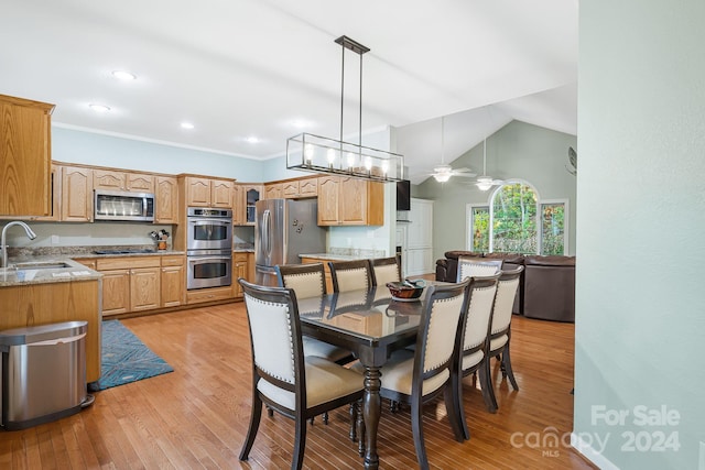 dining space with sink, ceiling fan with notable chandelier, light hardwood / wood-style floors, lofted ceiling, and crown molding