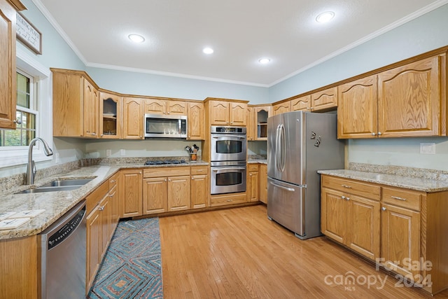 kitchen with ornamental molding, sink, appliances with stainless steel finishes, and light hardwood / wood-style floors