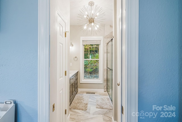 bathroom with vanity, walk in shower, and an inviting chandelier