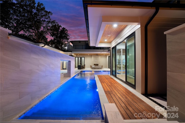 pool at dusk featuring a hot tub and a patio