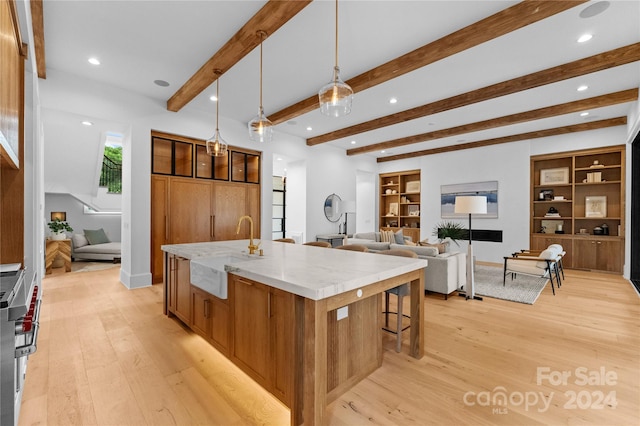 kitchen with a large island, light hardwood / wood-style flooring, sink, and hanging light fixtures