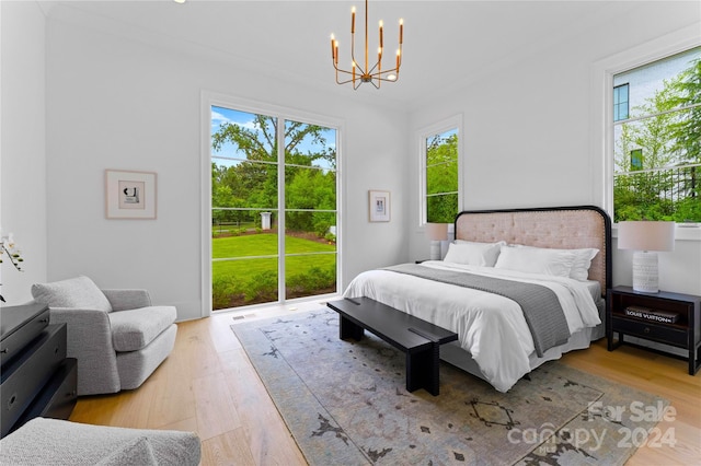 bedroom with light hardwood / wood-style floors, ornamental molding, an inviting chandelier, and access to exterior