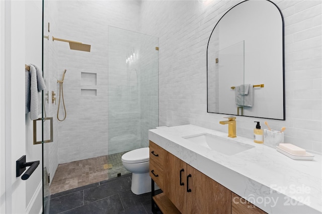 bathroom featuring tiled shower, tile patterned floors, toilet, vanity, and tile walls