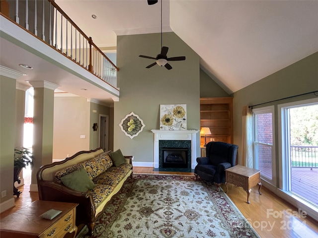 living room with wood-type flooring, ornamental molding, a fireplace, high vaulted ceiling, and ceiling fan