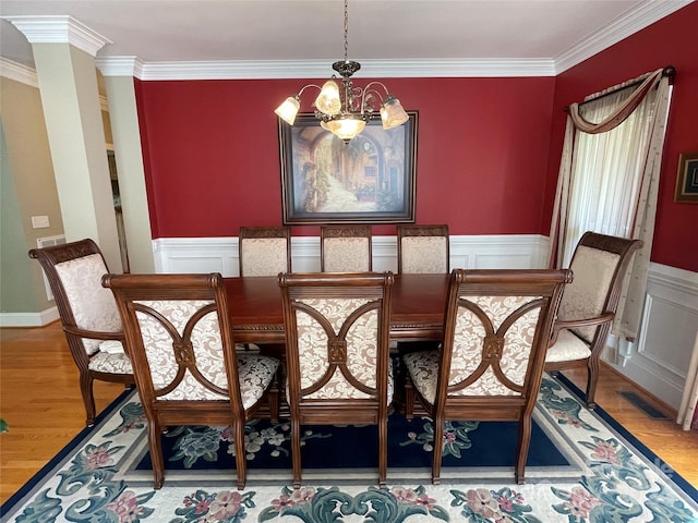 dining area with ornamental molding, decorative columns, light hardwood / wood-style flooring, and a notable chandelier