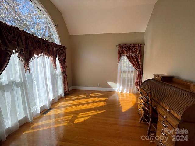 interior space with baseboards, wood finished floors, visible vents, and high vaulted ceiling