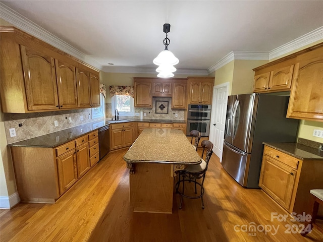kitchen featuring a kitchen breakfast bar, brown cabinetry, appliances with stainless steel finishes, a center island, and light wood-style floors