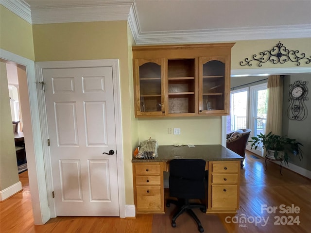 office featuring light wood-style floors, ornamental molding, baseboards, and built in desk