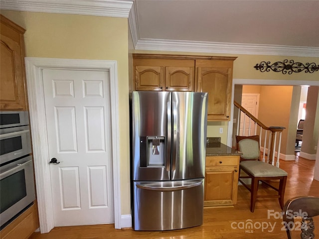 kitchen featuring dark stone countertops, light hardwood / wood-style floors, appliances with stainless steel finishes, and ornamental molding