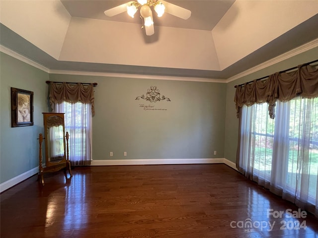 empty room with crown molding, ceiling fan, a tray ceiling, and dark hardwood / wood-style flooring