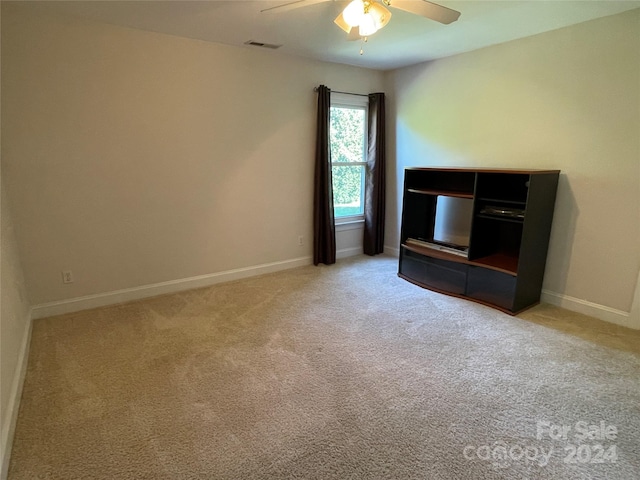 interior space with baseboards, a ceiling fan, carpet flooring, and visible vents