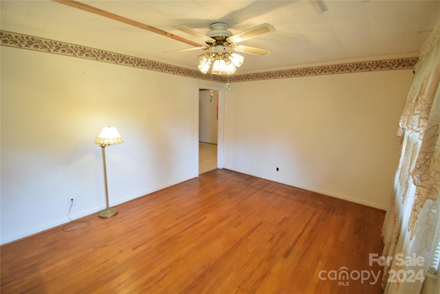 empty room with crown molding, wood-type flooring, and ceiling fan