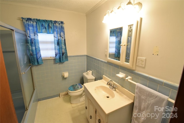 bathroom featuring a shower with door, vanity, toilet, and tile walls