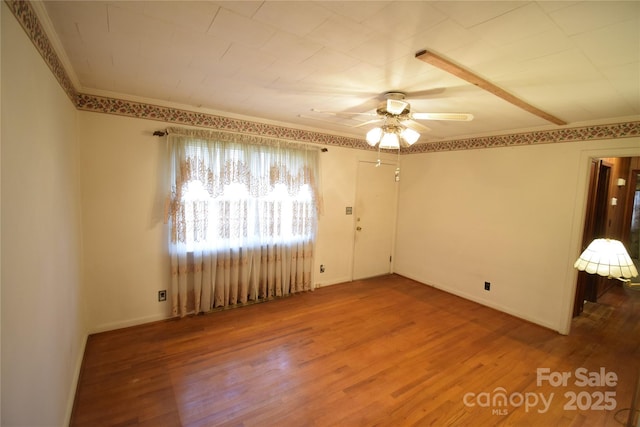 empty room featuring crown molding, baseboards, ceiling fan, and wood finished floors