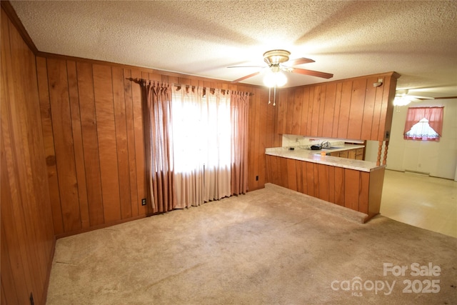 unfurnished room featuring a ceiling fan, wood walls, and light carpet