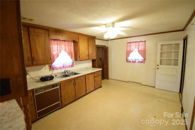 kitchen featuring brown cabinets, a sink, dishwasher, light countertops, and visible vents