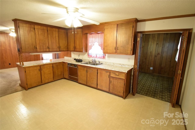 kitchen featuring a ceiling fan, brown cabinets, light countertops, a sink, and black dishwasher