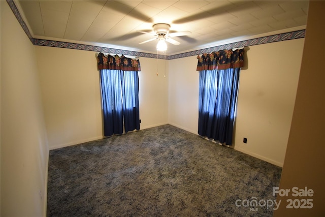 spare room featuring dark colored carpet, a ceiling fan, baseboards, and a wealth of natural light