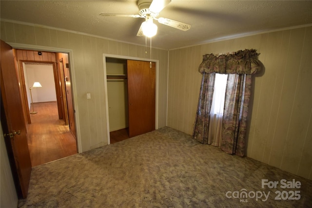 unfurnished bedroom featuring carpet floors, ornamental molding, a closet, and ceiling fan