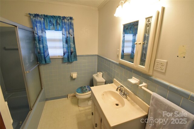 bathroom with crown molding, vanity, toilet, tile walls, and a wainscoted wall
