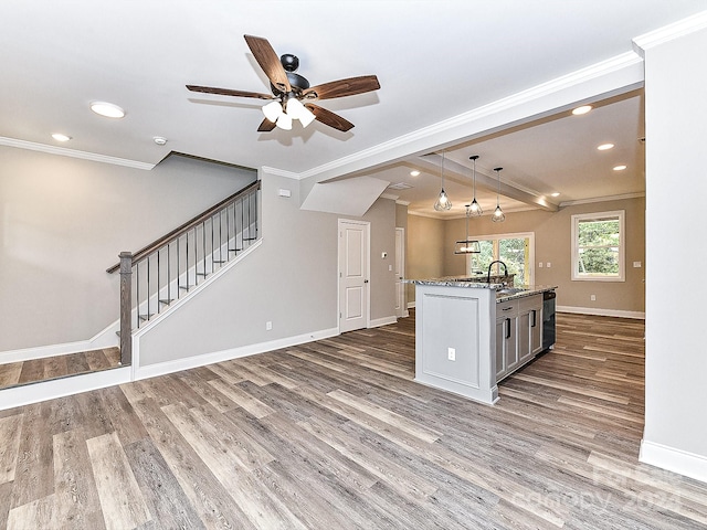 kitchen featuring ceiling fan, crown molding, pendant lighting, a kitchen island with sink, and hardwood / wood-style flooring