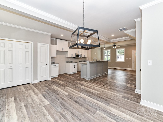 kitchen with white cabinetry, an island with sink, wood-type flooring, and decorative light fixtures