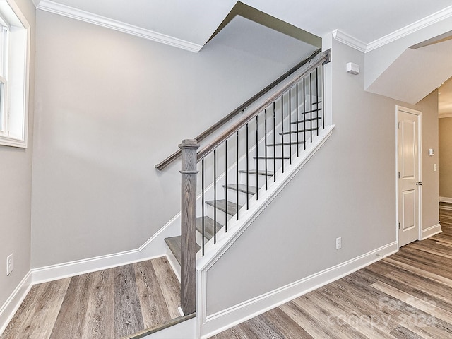 staircase with ornamental molding and hardwood / wood-style flooring