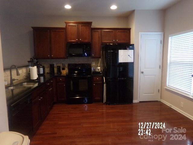 kitchen with black appliances, plenty of natural light, dark hardwood / wood-style flooring, and sink