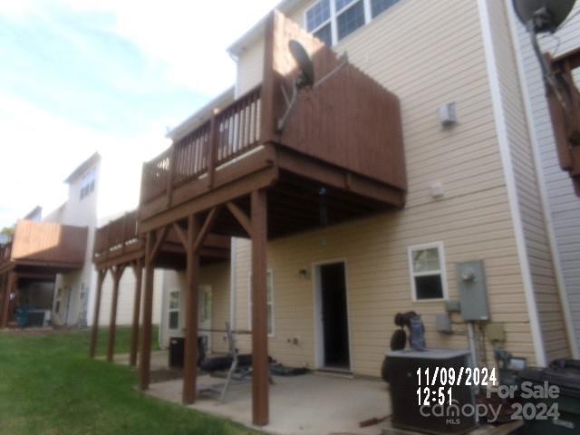 back of property with a wooden deck, a patio area, and a yard