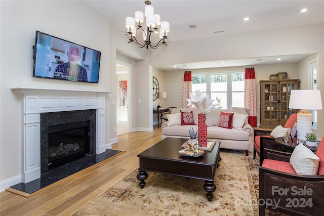 living room with light hardwood / wood-style floors, an inviting chandelier, and a fireplace