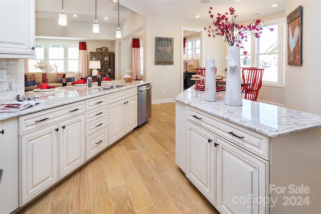 kitchen featuring stainless steel dishwasher, sink, pendant lighting, and plenty of natural light