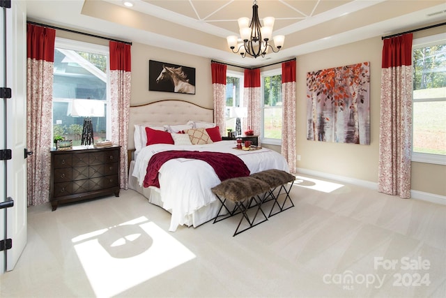 carpeted bedroom featuring multiple windows, a notable chandelier, and a tray ceiling