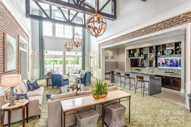 living room featuring a towering ceiling and brick wall