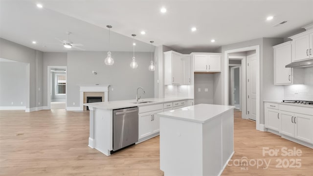 kitchen with a kitchen island, a sink, open floor plan, light countertops, and stainless steel dishwasher